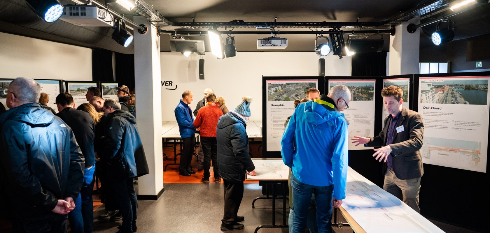 personen in een ruimte waarin infoborden en posters staan