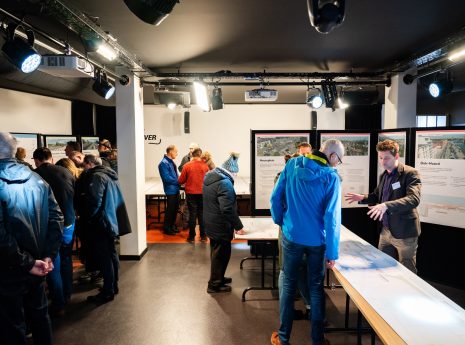 personen in een ruimte waarin infoborden en posters staan