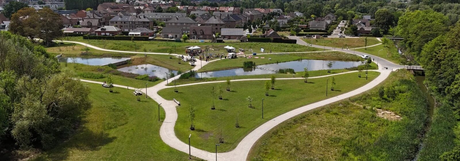 overzicht van het Wilderpark: combinatie van gras, waterpartijen en een fietsweg