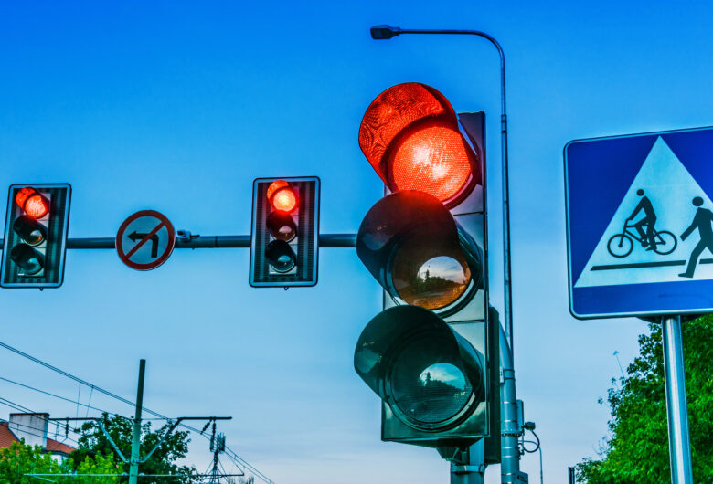 Verkeerslichten boven een kruispunt in de stad. Een verkeersbord met een voetganger en een fiets.
