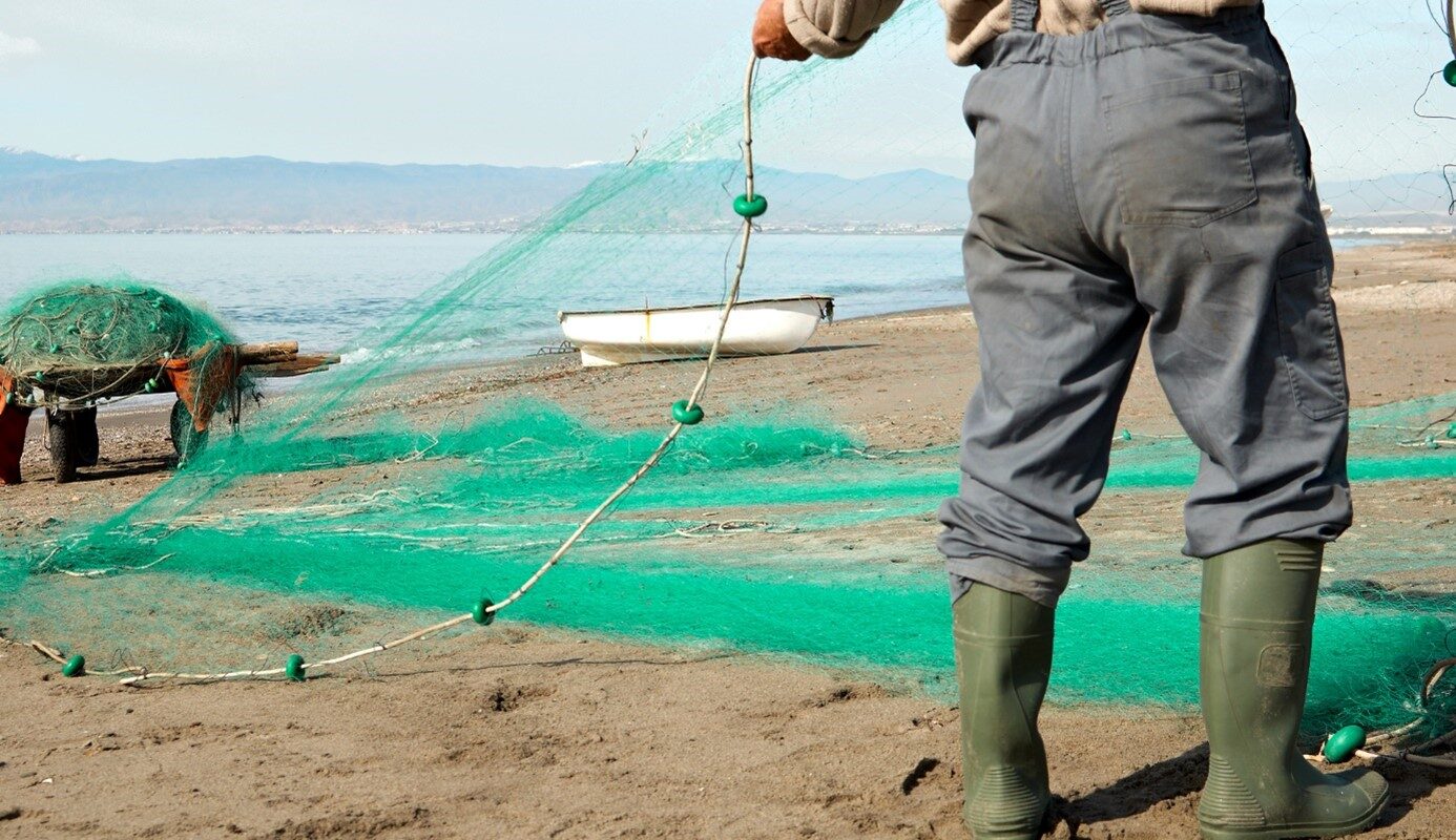 fisherman on shore with green fishing nets