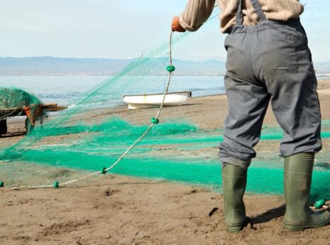 fisherman on shore with green fishing nets
