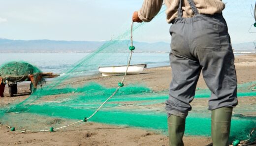 fisherman on shore with green fishing nets