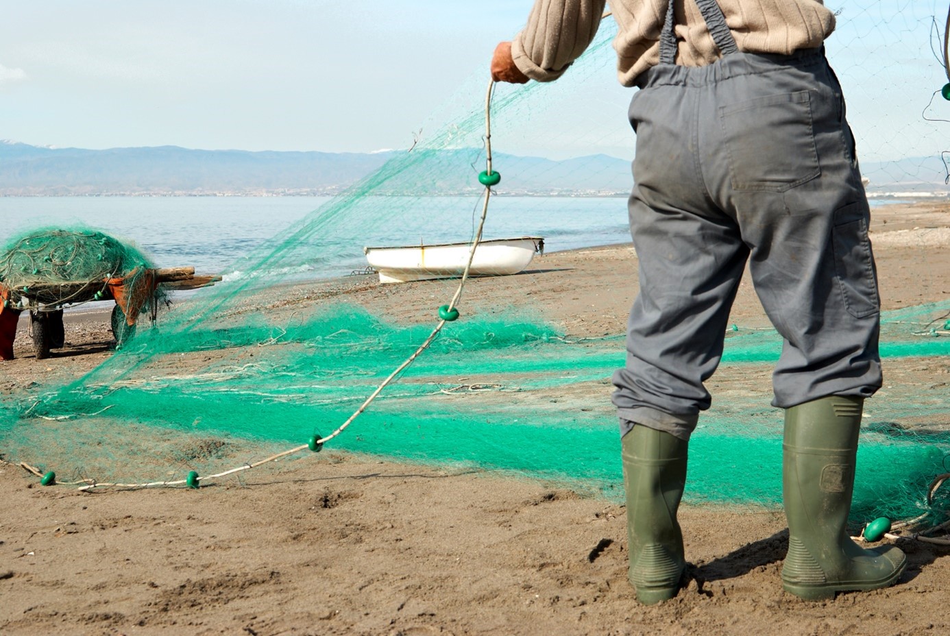 fisherman on shore with green fishing nets