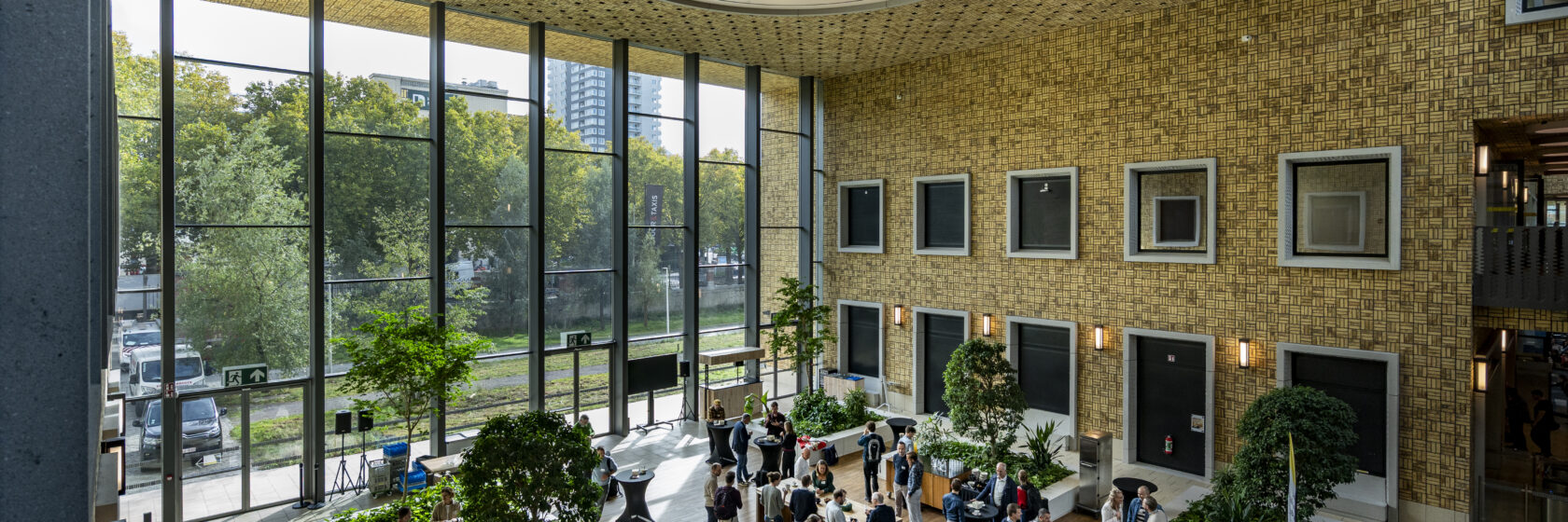 interieur Herman Teirlinck: grote glaspartijen, groene zones, mensen die in een lobby vertoeven