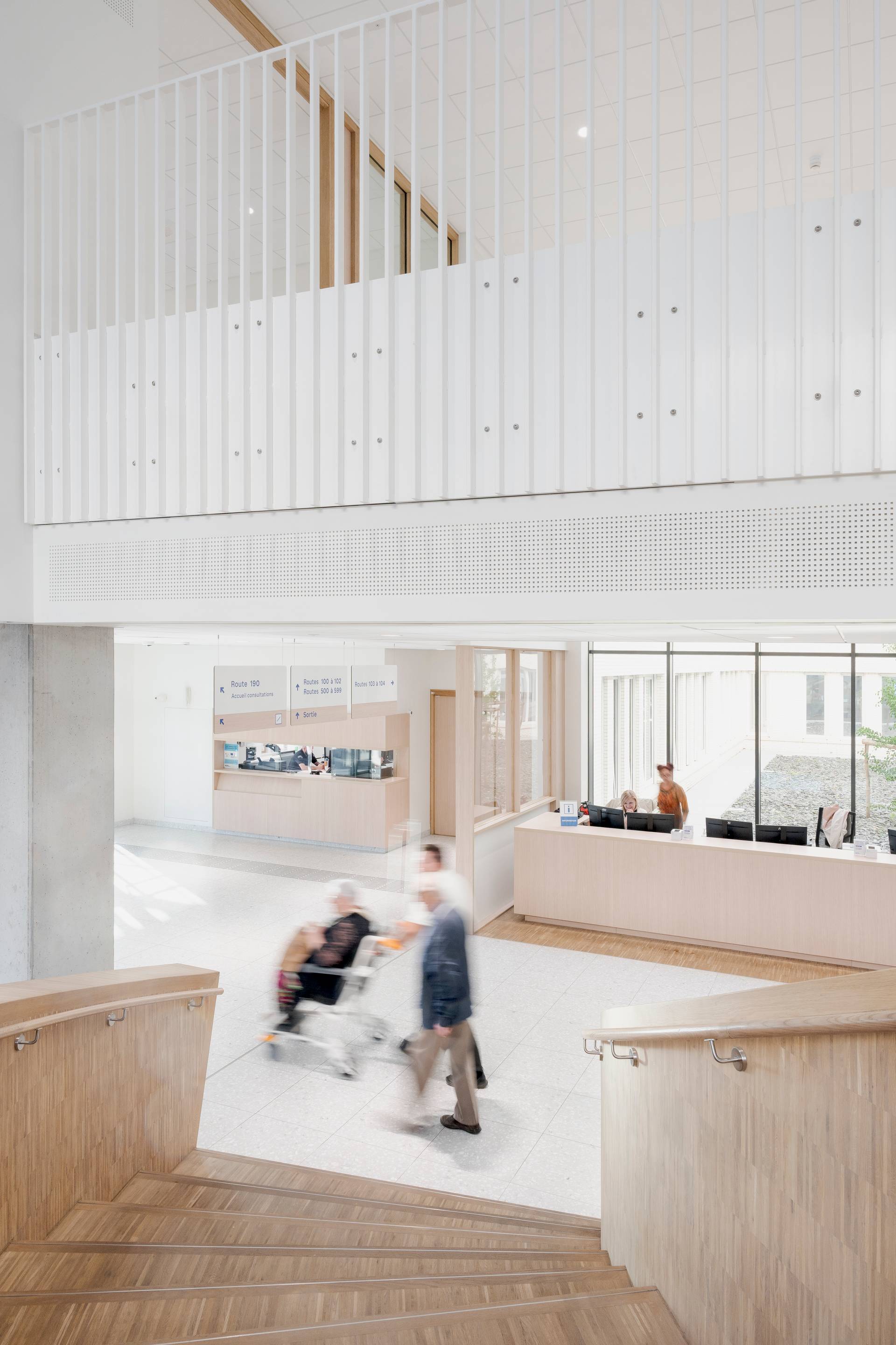 interior photo of the new Grand Hopital de Charleroi hospital, with a view on the reception desk from the circular timber staircase