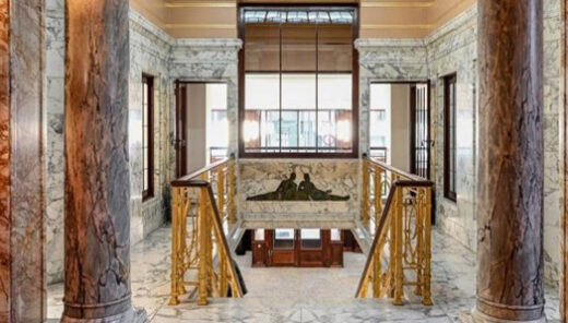 art deco ruimte met roze marmeren muren en goude trapleuningen