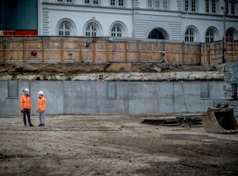 photo of an excavation site for a building project, with two Sweco workers in safety gear