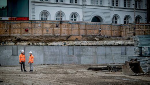 photo of an excavation site for a building project, with two Sweco workers in safety gear