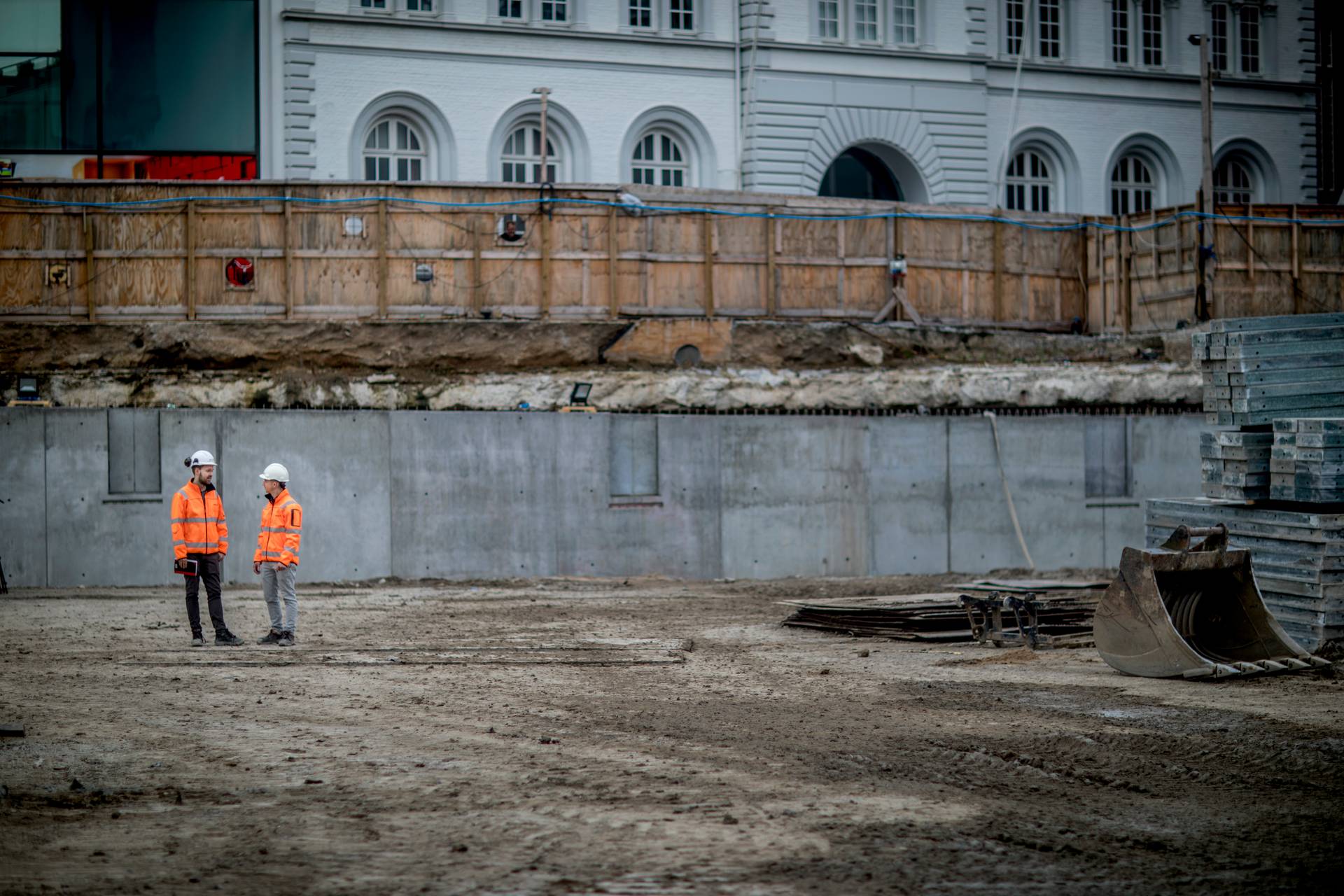 photo of an excavation site for a building project, with two Sweco workers in safety gear