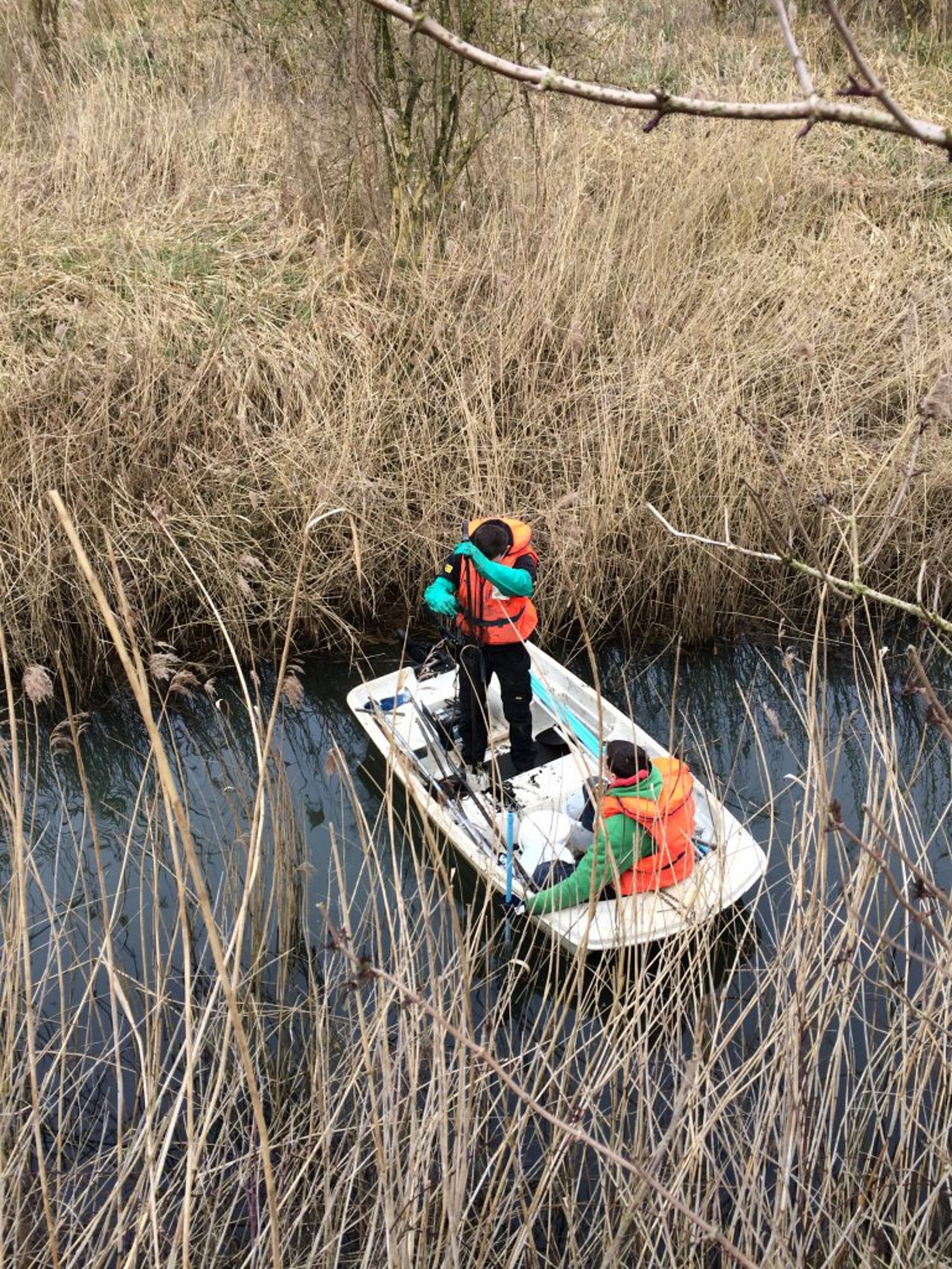 photo of two men in a boat in a marsh taking samples for water and soil investigation