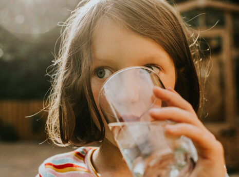 A little girl drinks a refreshing glass of water