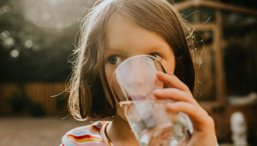 A little girl drinks a refreshing glass of water
