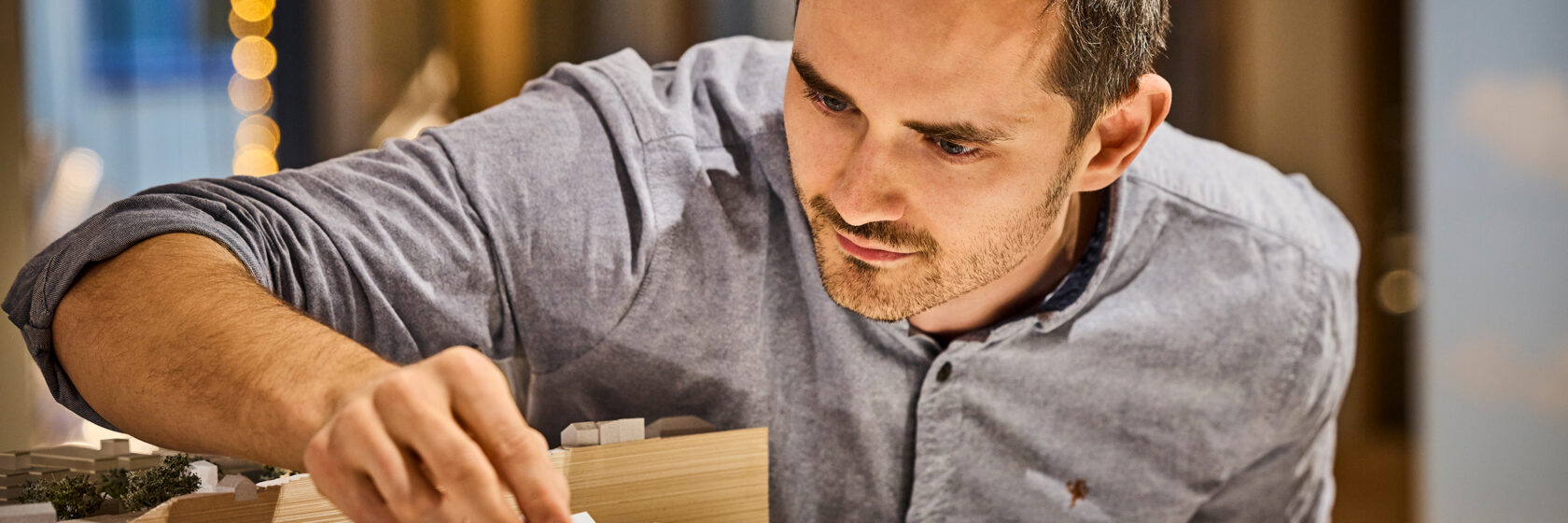 photo of a man handling an architectural model of a cityscape