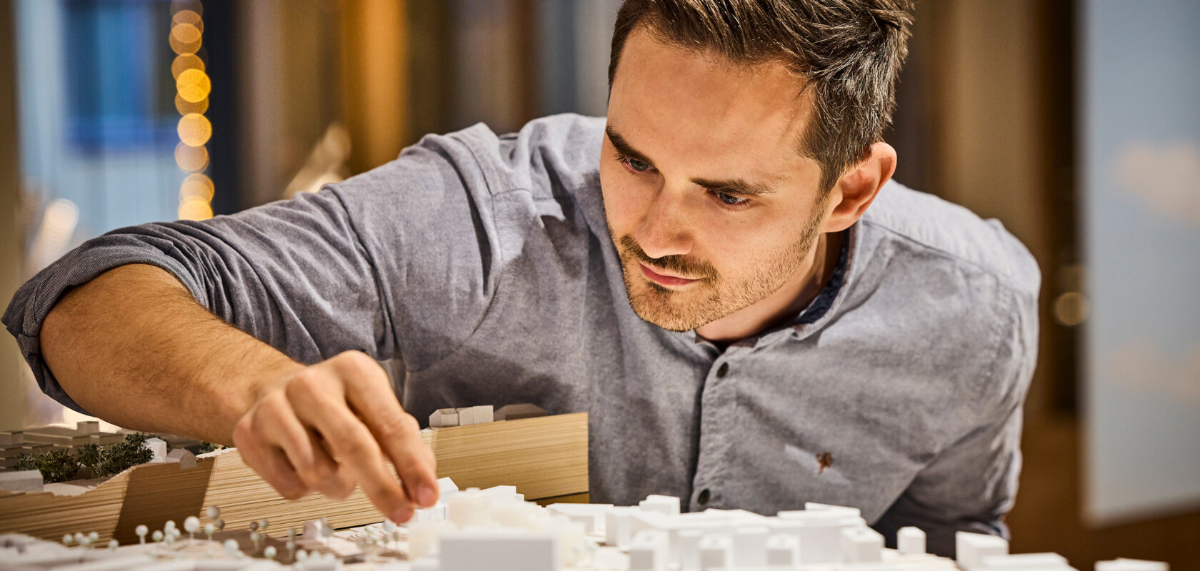 photo of a man handling an architectural model of a cityscape