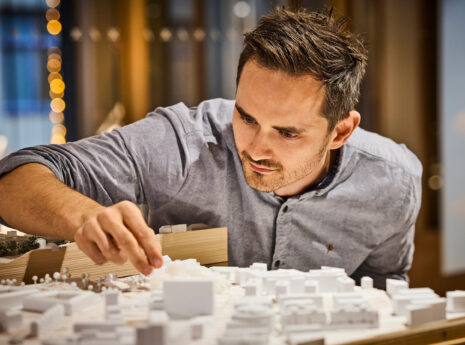 photo of a man handling an architectural model of a cityscape
