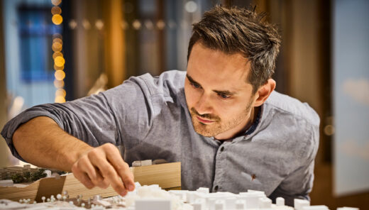 photo of a man handling an architectural model of a cityscape